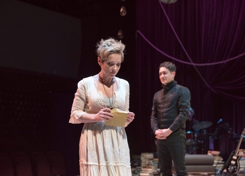A photo of the original stage play of Onegin. Tatiana stands in the centre of the stage holding a letter. Onegin is behind her. Their expressions are difficult to parse.